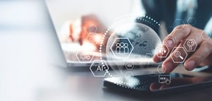 Tropical Hub: Mãos digitando em notebook e tablet com ícones digitais de IA, dados e pessoas, representando automação de marketing integrada a tecnologia, análise de dados e processos inteligentes.