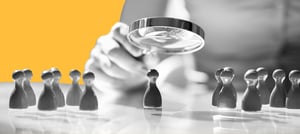 Pessoa segurando uma lupa focando em um peão de xadrez