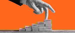 mão apontando para uma escada, onde está escrito em seus degraus as palavras visão, plano, ideia, esforço e sucesso 