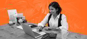 Mulher trabalhando como corretora com um notebook, conferindo um CRM imobiliário - Tropical Hub